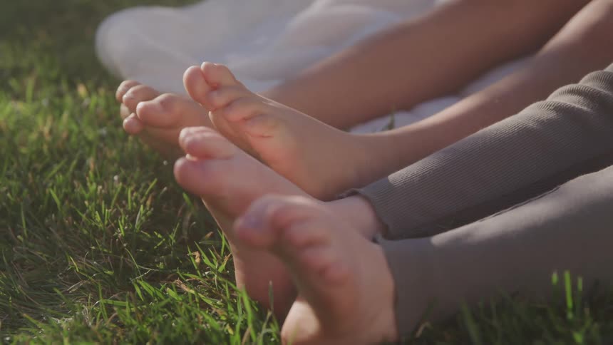 Two people wiggle their toes on the grass