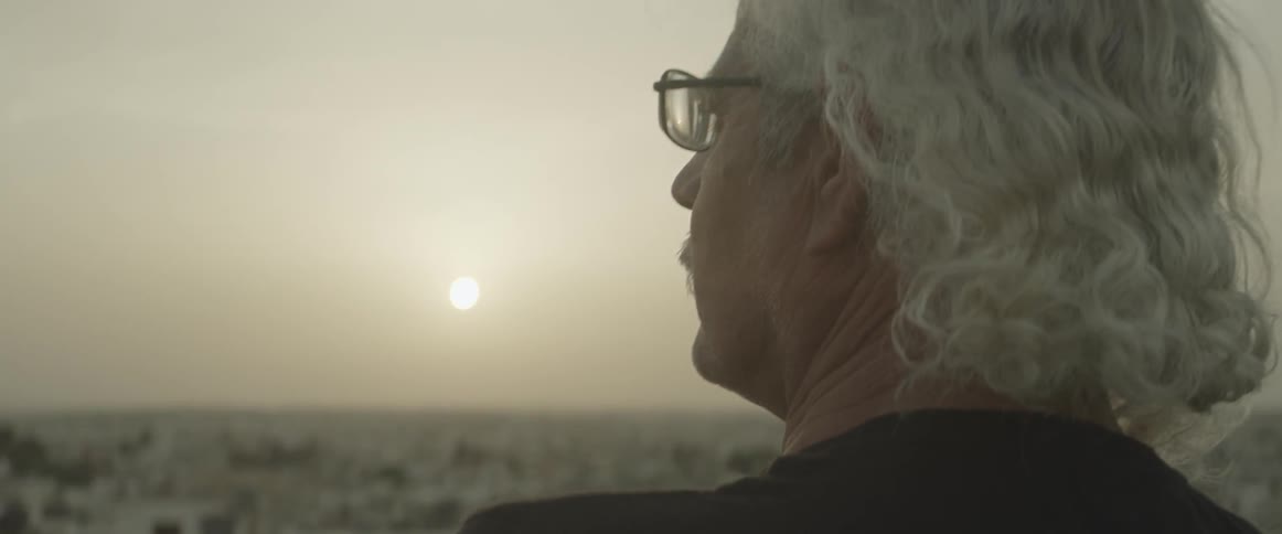 An older man is looking out over a city at dawn or dusk
