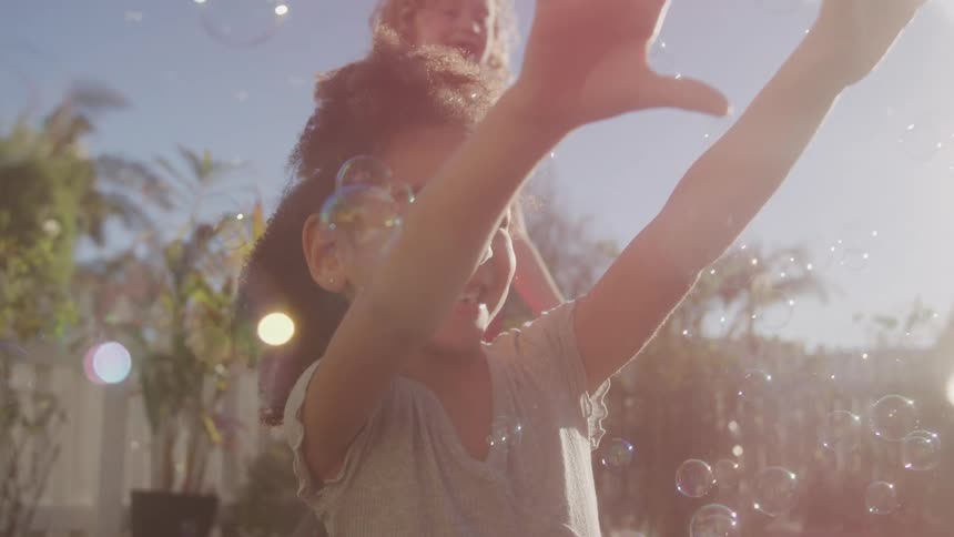 Two children in a backyard with soap bubbles