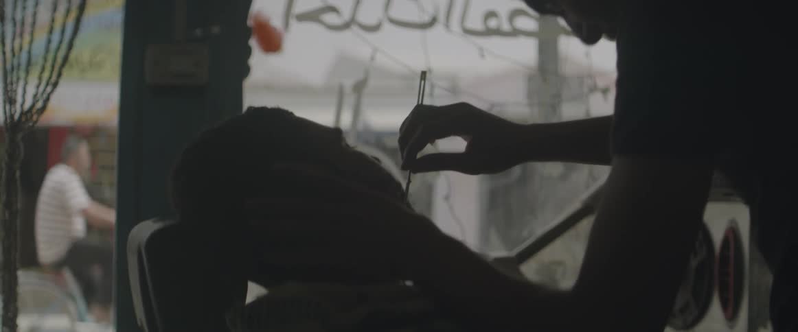 A barber shaves a mans beard