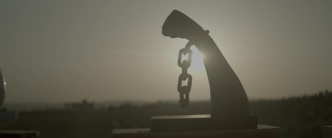 The sun shines behind a carving of a fist with a chain