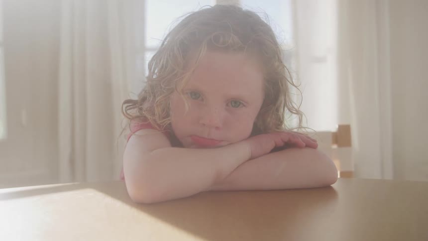 A child sits sadly at a table