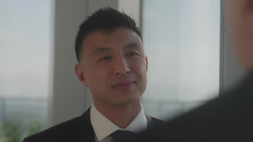 The video shows a man in a dark suit and white shirt looking directly at the camera and smiling slightly his expression suggests confidence and professionalism