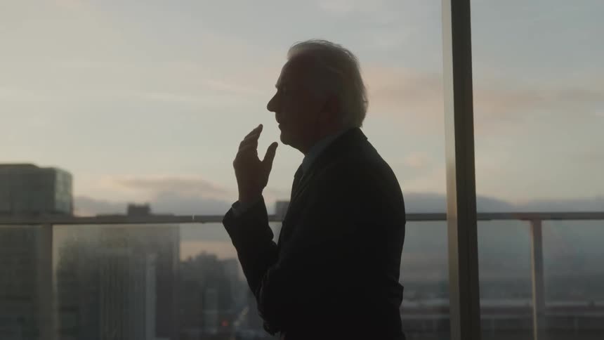 Elderly man in a suit walking through an office room thoughtfully