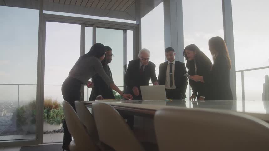 Group of people around a laptop at a table in an office meeting