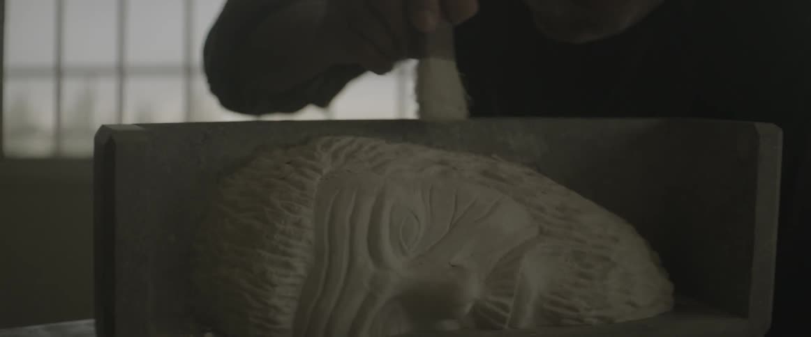 A man brushes dust off a sculpture