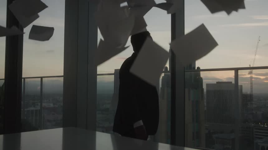 Man in an office room throwing papers up
