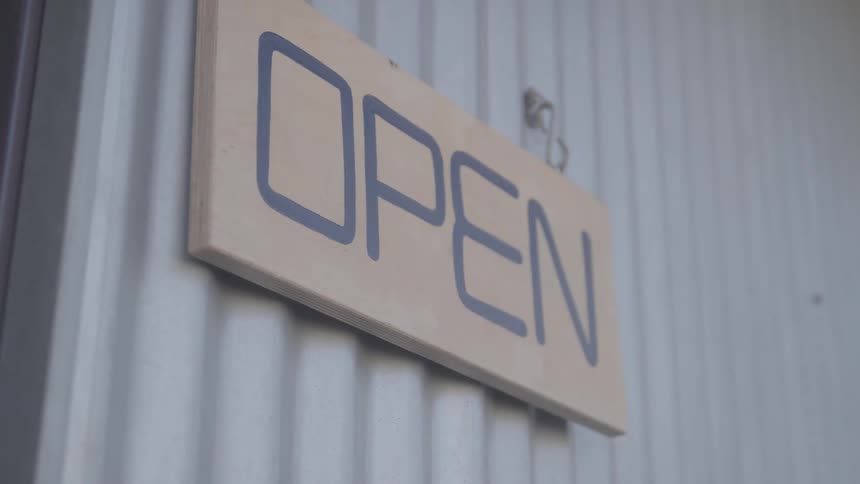 Closeup of a metal wall with a sign saying open