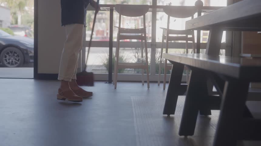 Person sweeps floor near entrance of cafe