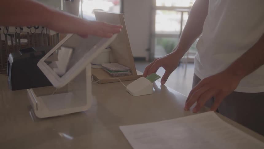 Customer hands card at tablet checkout counter