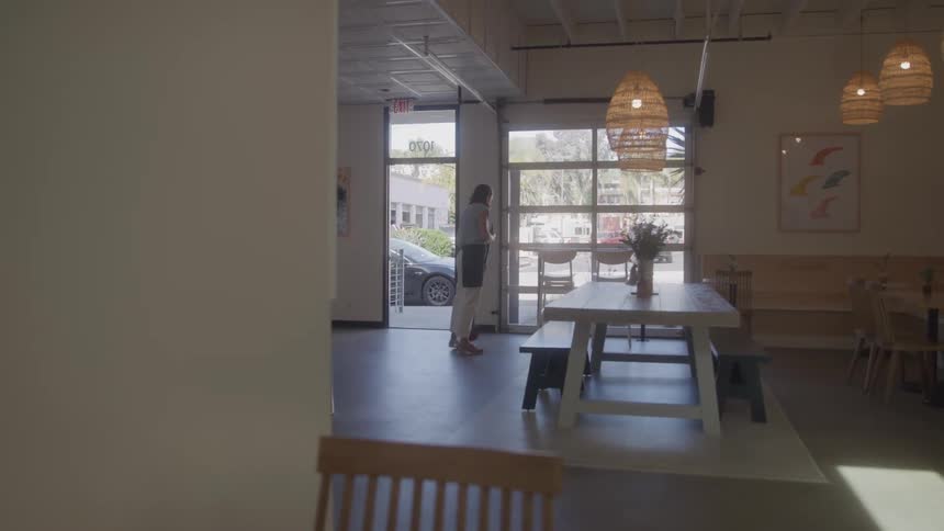Person sweeps floor in bright modern cafe
