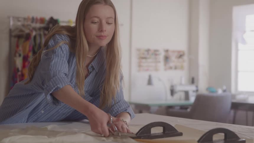 A woman cuts fabric on a table in a sewing studio