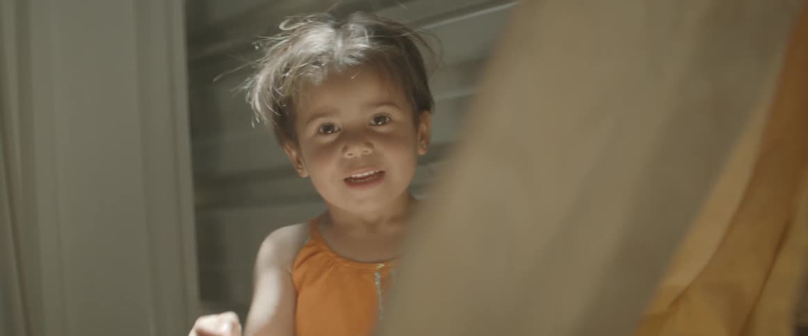 A toddler plays with a curtain