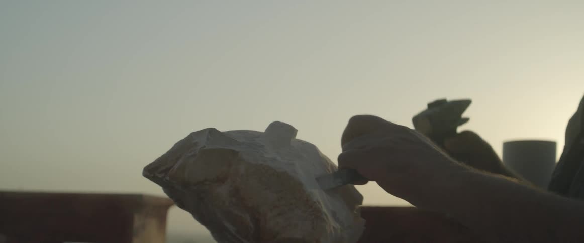 A person is chiseling a piece of stone