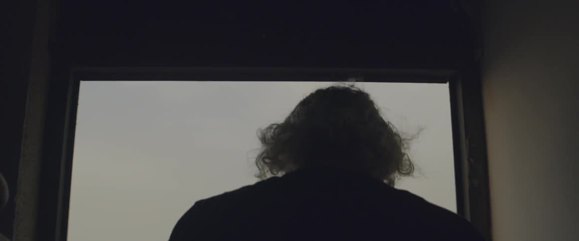 An elderly man walks on a rooftop
