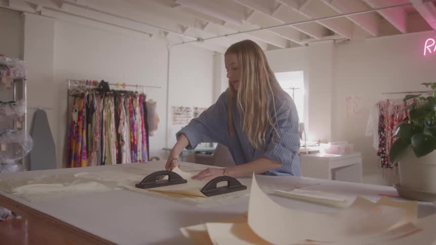 The tailor is cutting with her scissors