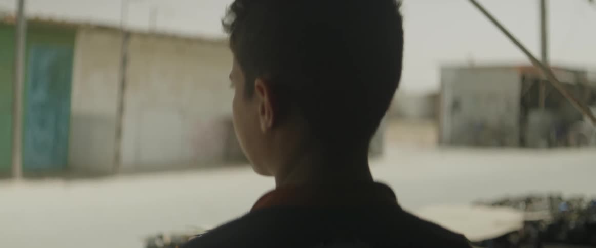 A boy is looking over a barren lot