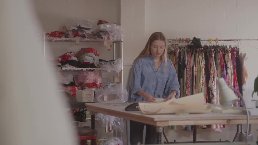 The tailor is working at the large table