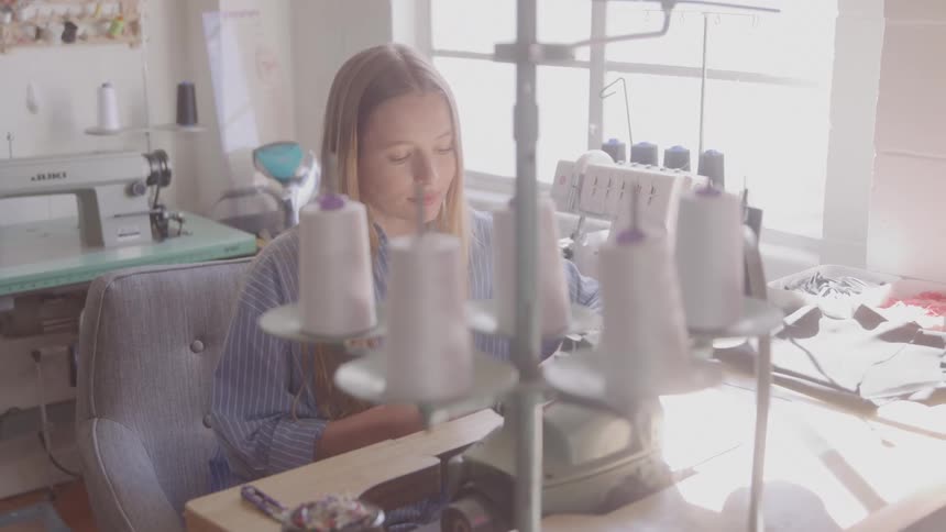 Blonde woman working at a sewing table with machines