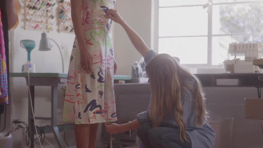 Fashion designer takes measurements of customer in bright studio