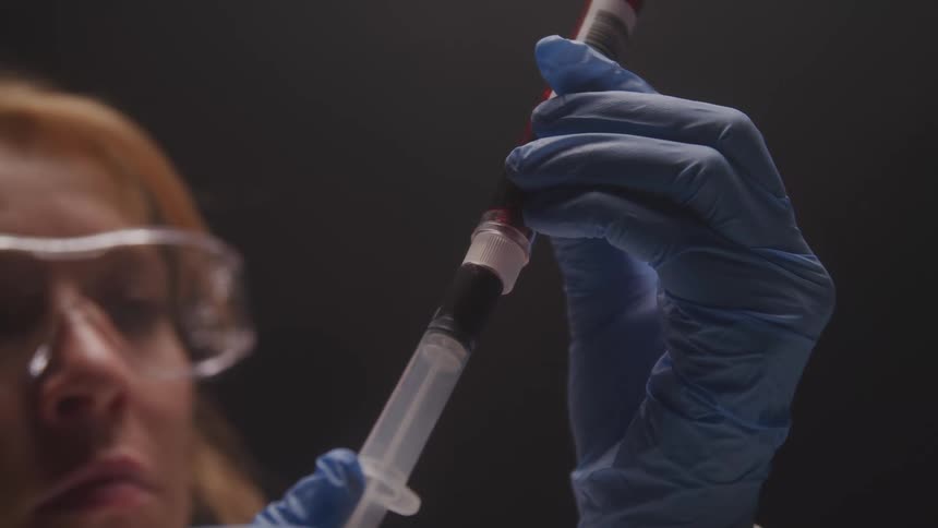 Woman with gloves working with a syringe in a laboratory