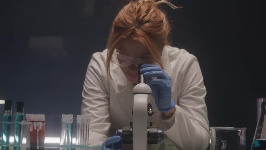 Woman in lab coat using microscope in a laboratory