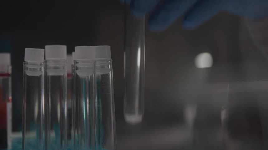Gloved hand picking up an empty test tube