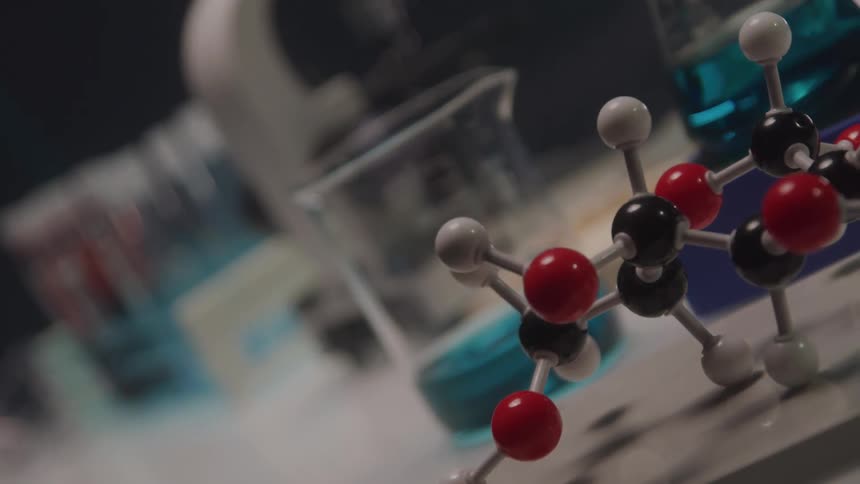 A table in a lab contains test tubes flasks and a microscope