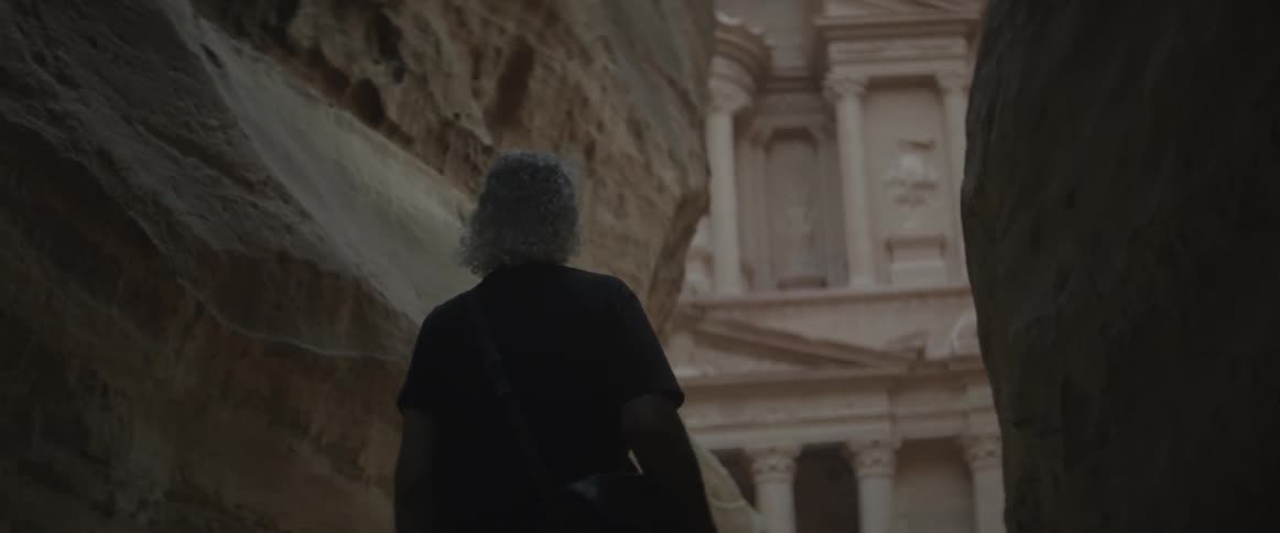 A man walks towards some stone pillars ahead