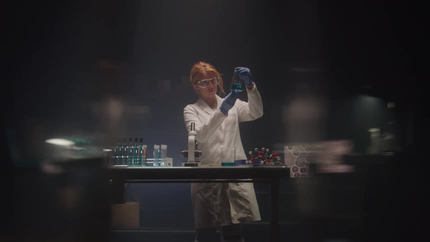 Woman in white coat and gloves working with test tubes in a laboratory