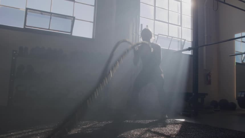 Silhouette of a woman doing rope training in a crossfit gym