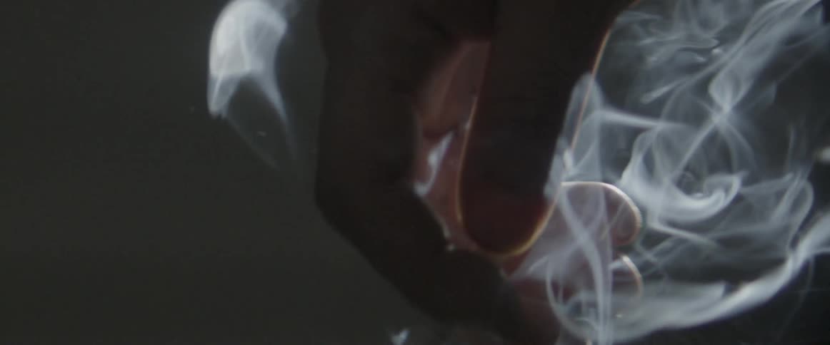 A hand holding a cigarette in a dim room