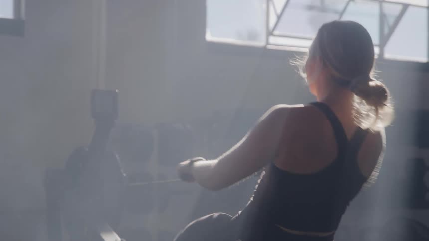 A young woman uses a rowing machine in the gym during daytime