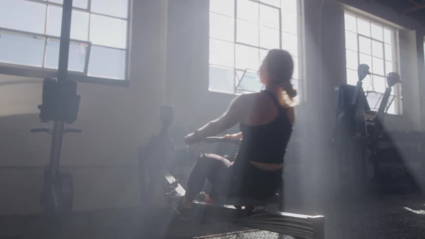 Blonde woman doing aerobic exercise on a machine in a gym