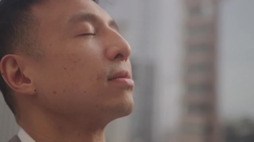 A man gazes upward thoughtfully against a blurred city background