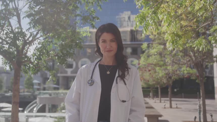 The doctor is smiling in front of the building