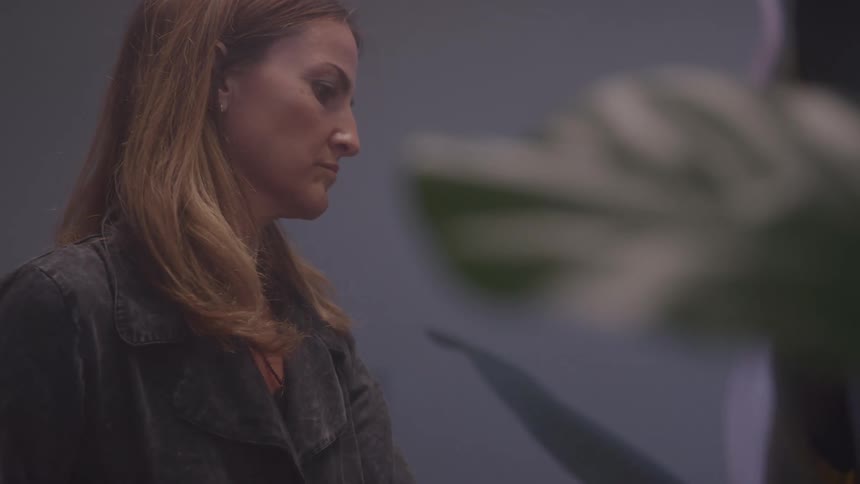 The video shows a side profile of a woman with long light brown hair appearing focused as she looks down and to her right she is wearing a dark jacket a filmsupply watermark is visible across the center of the frame