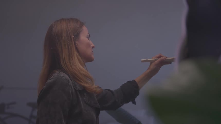 Woman paints a canvas with a brush indoors focused on her artistic expression