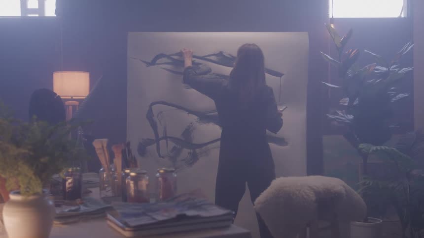 Female artist paints abstract shapes on large canvas