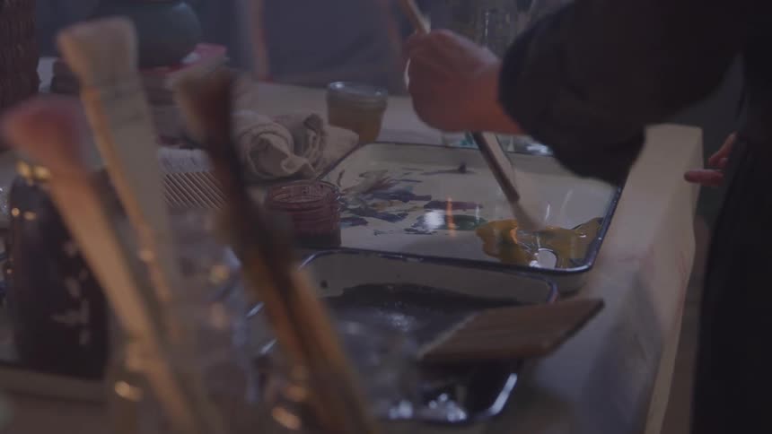 Woman holding a paintbrush and putting it in a bucket of paint