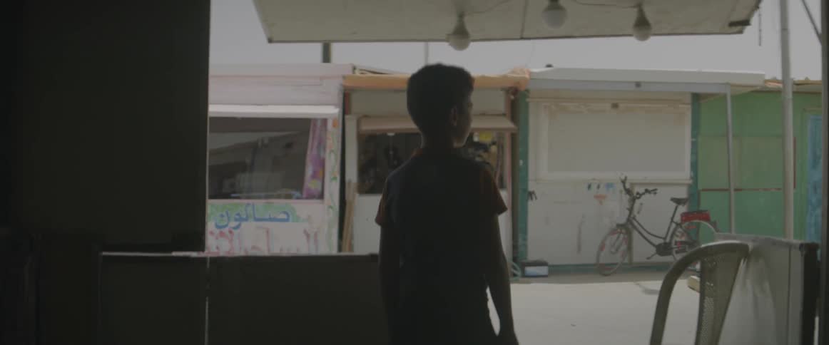 A boy looks out from under an awning