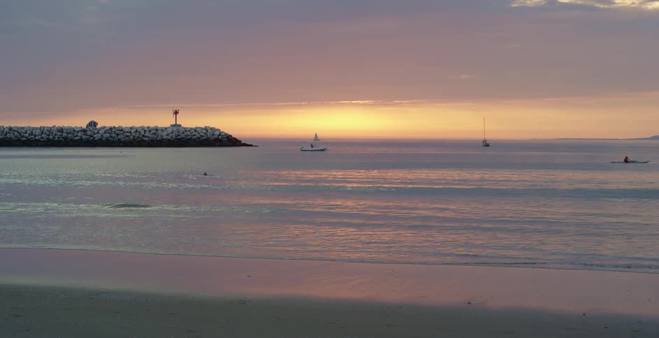 Landscape of a beach with boats at dawn with a reddish sky