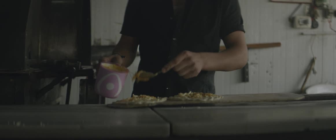 A man spreads an ingredient on dough