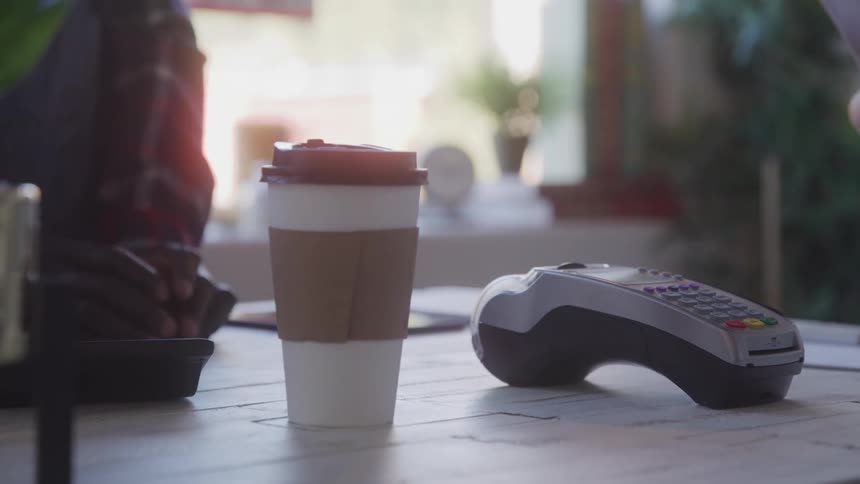 A person swiping their credit card on a card machine to buy a coffee