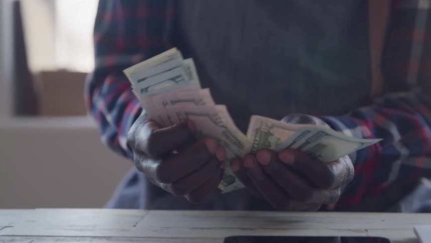 Man sitting at a desk counts paper money during the daytime