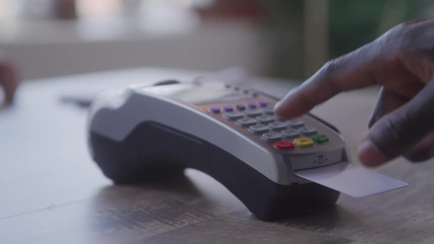 Hand inserting a credit card into a payment machine entering the pin and then removing the card