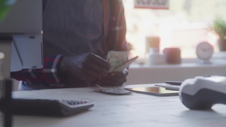 The worker counts money at the counter of the shop