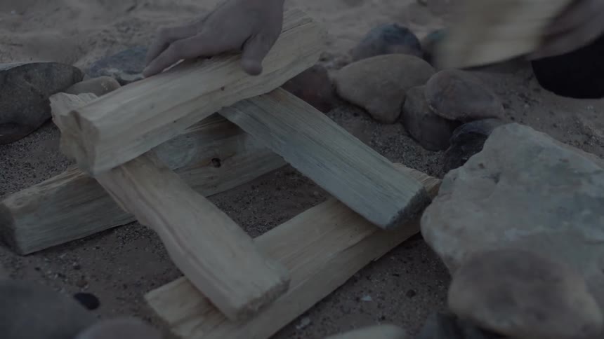 Person places kindling in a formation to start a campfire