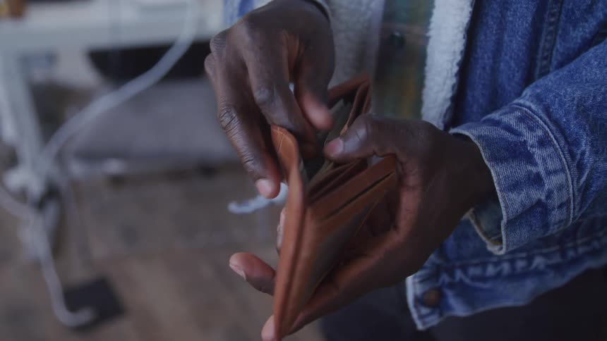 Pair of hands of a man counting banknotes inside a wallet
