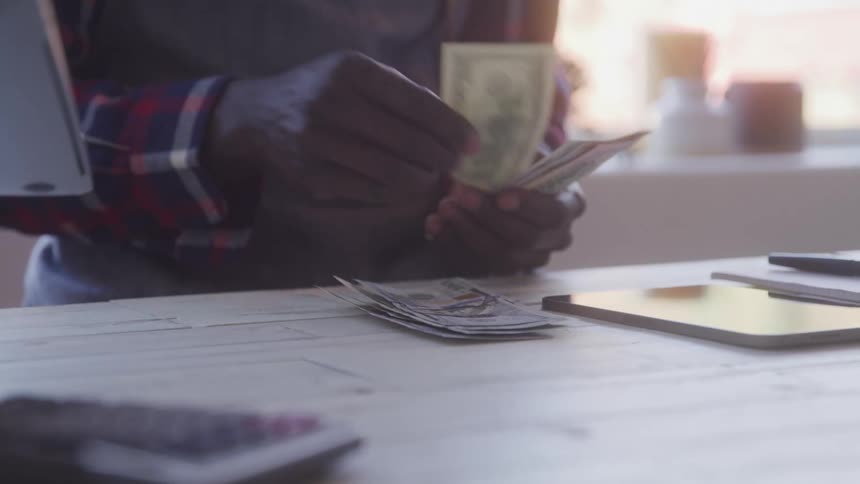 The man is counting out money on the table